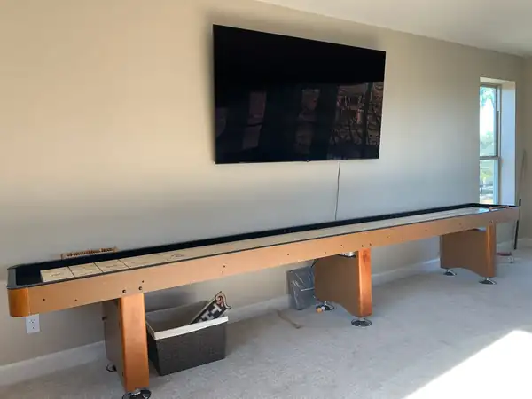 shuffleboard table delivered and set up in a home game room